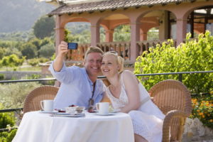 Happy couple taking self-portrait with camera on cafe patio - celebrations weddings mallorca 1 - Hotel Rural Monnaber Nou Mallorca